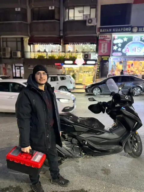 Çilingir ustası, motoru ve alet çantasıyla sokakta